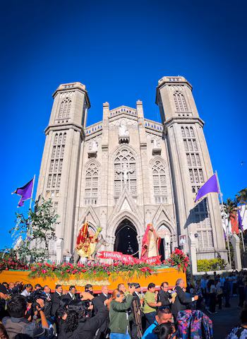 Платформа для процессии с религиозными статуями Иисуса верхом на осле и еще одной фигурой. Набор украшен красными цветами, листвой и пальмами.