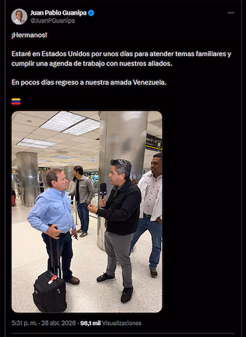 Хуан Пабло Гуанипа в синей рубашке держит чемодан. Репортер берет у него интервью с микрофоном в аэропорту, на заднем плане другие люди.