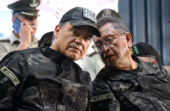 Заместитель министра социальной защиты и контролируемых веществ Эрнесто Хустиниано (i) с министром правительства Марко Антонио Овьедо. (Фото АЙЗАР РАЛЬДЕС/AFP)